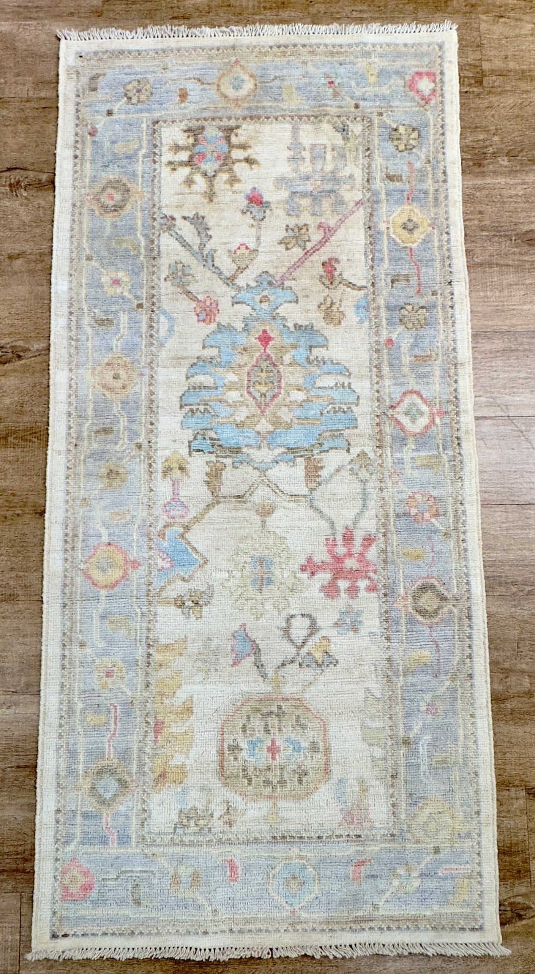 Knotted Couture hand knotted wool oushak runner in colors of blue, ivory, beige, rust, and camel