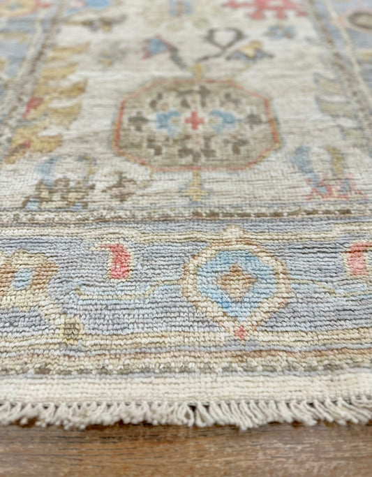 Knotted Couture hand knotted wool oushak runner in colors of blue, ivory, beige, rust, and camel