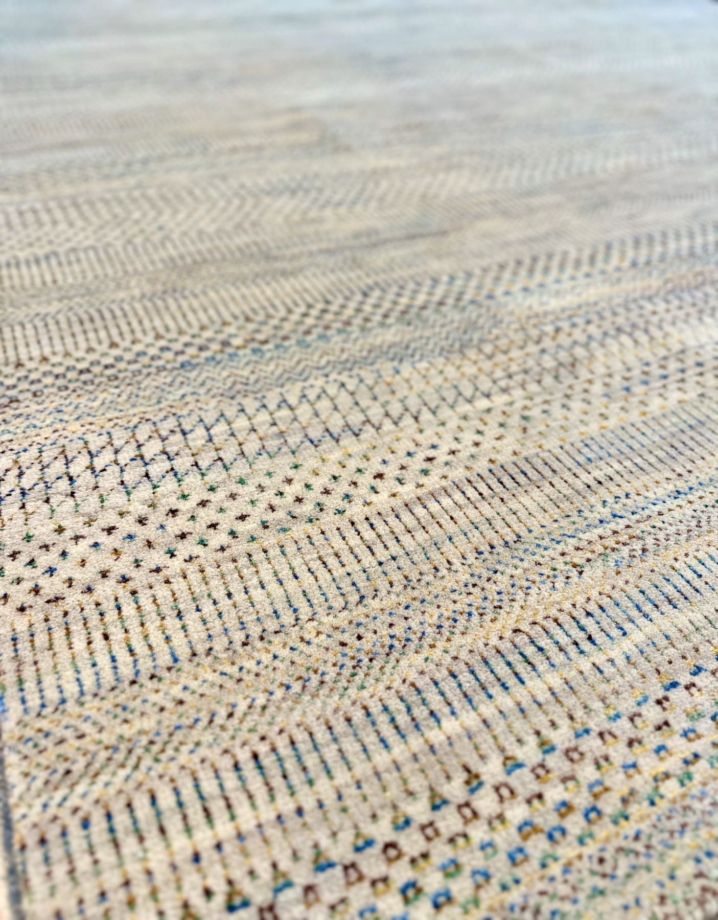 Neutral background wool hand knotted rug with jewel tone accents in a casual, modern palette.