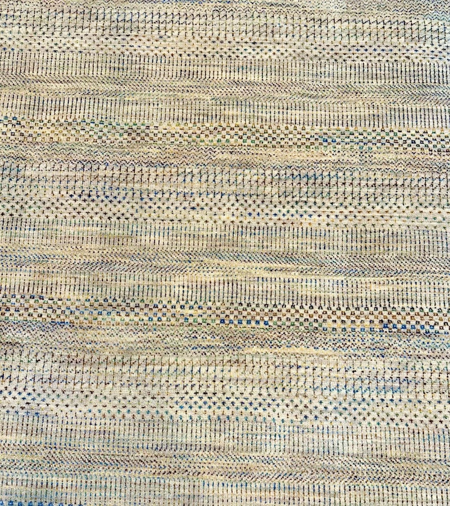 Neutral background wool hand knotted rug with jewel tone accents in a casual, modern palette.