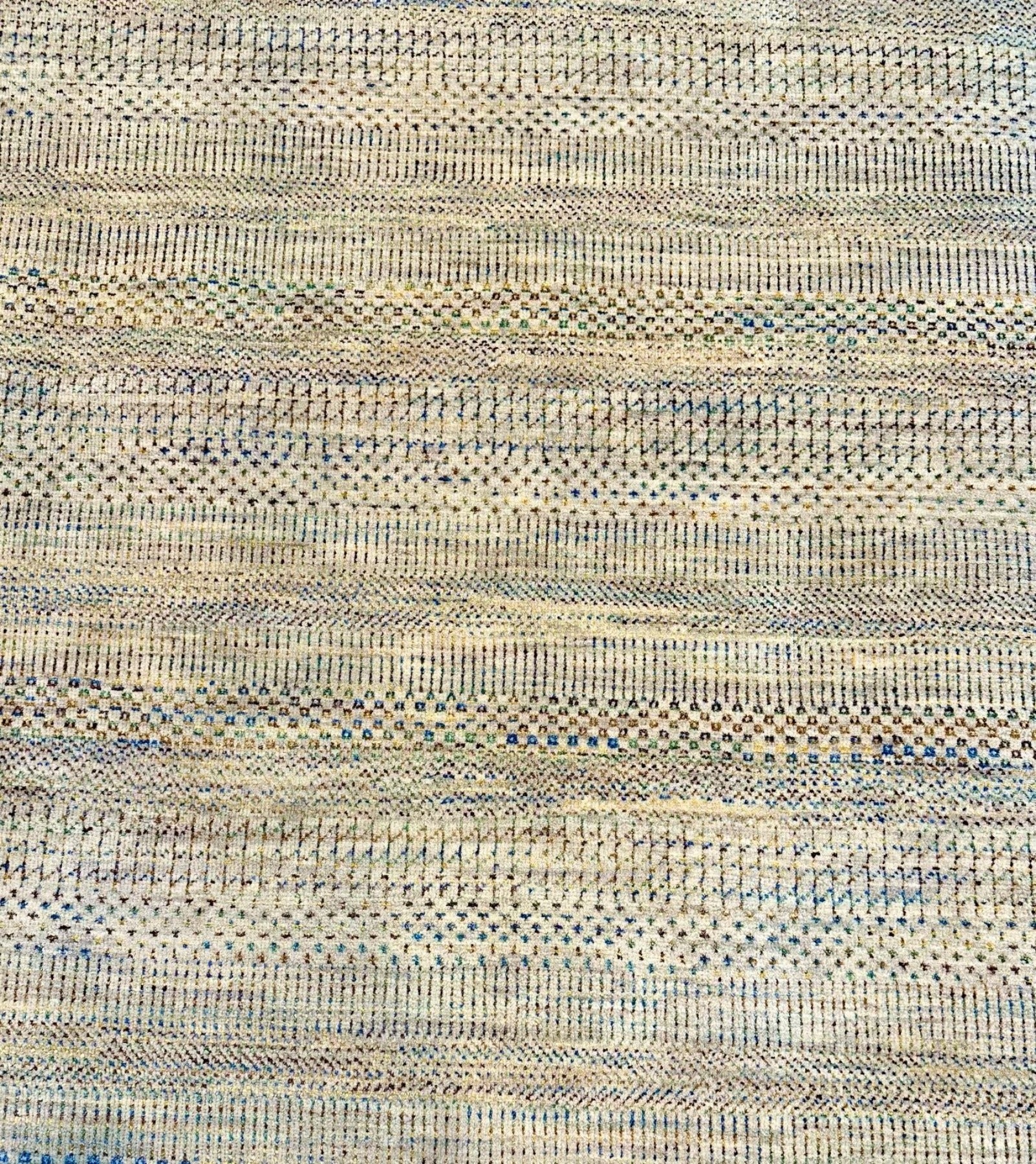 Neutral background wool hand knotted rug with jewel tone accents in a casual, modern palette.