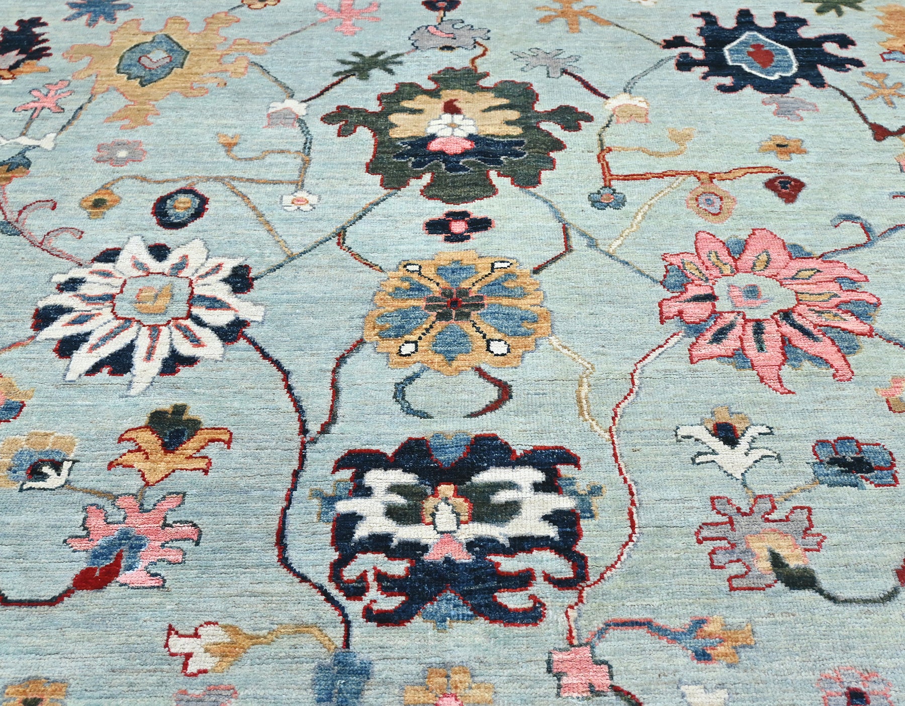 Vibrant wool Oushak rug size 9 x 12 with a blue center and shades of green, coral, blue, gray, and gold.