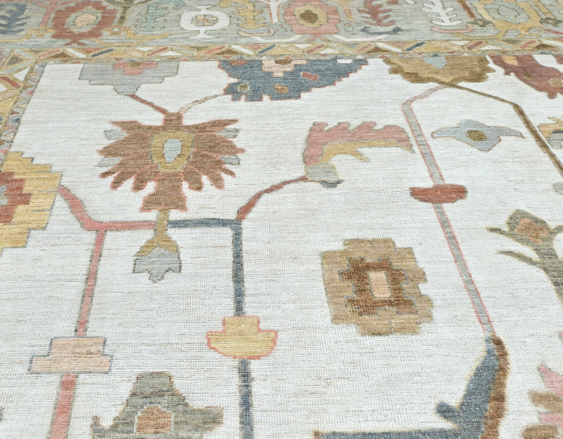 Oversized 13 x 17 handknotted oushak rug in soft, muted colors with a detailed border and overall pattern