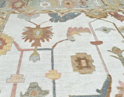 Oversized 13 x 17 handknotted oushak rug in soft, muted colors with a detailed border and overall pattern